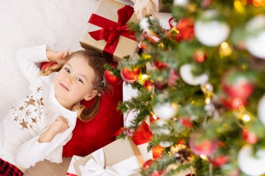 Mutlu küçük kız evde Noel ağacının altında yatıyor.