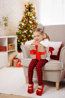 Mutlu küçük kız Noel süslemeli odasında hediyeyle