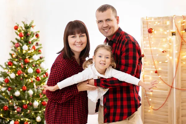 快乐的父母在圣诞树旁牵着女孩的手 — 图库照片