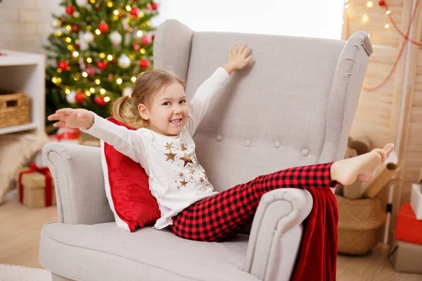 Pijamalı Küçük Kız Noel Süslemeli Odada Koltukta Eğleniyor — Stok fotoğraf