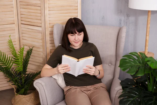 Happy Brunette Woman Reading Interesting Book Armchair — Stok fotoğraf