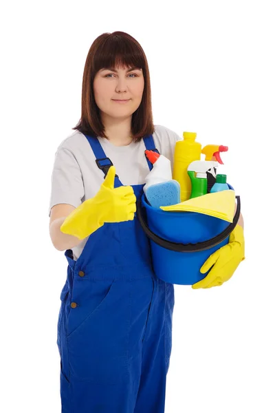 家事と掃除のコンセプト 青の制服を着た若い女性のクリーナーの肖像画と白の背景に隔離された洗浄装置と親指を持つ黄色の手袋のバケツを保持 — ストック写真