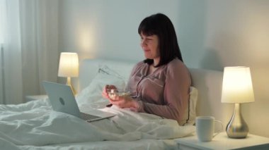 Genç gülen kadın film izliyor ya da laptopta komik bir video yatak odasında oturuyor.