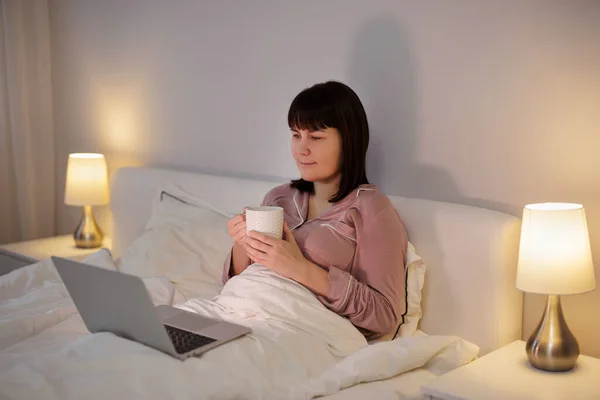 Mulher Usando Laptop Enquanto Deitado Sua Cama Com Xícara Chá — Fotografia de Stock