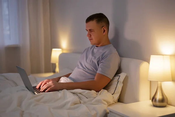 Hombre Joven Usando Ordenador Portátil Mientras Está Acostado Cama Casa —  Fotos de Stock