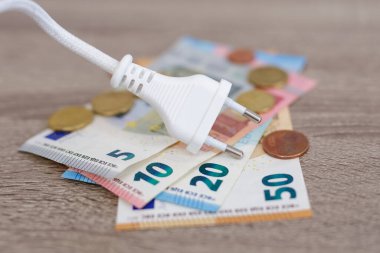 elektrik maliyeti ve pahalı enerji kavramı - Euro banknotları ve sikkeleri ile elektrik güç kablosu dolgusu