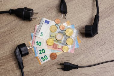 Pahalı elektrik kavramı - Masadaki elektrik prizleri ve Avrupa para banknotları ve sikkelerine yakın çekim