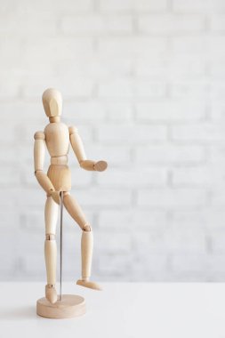 Beyaz tuğla duvar arkaplanının üzerinde kopyalama alanı olan tahta insan figürü