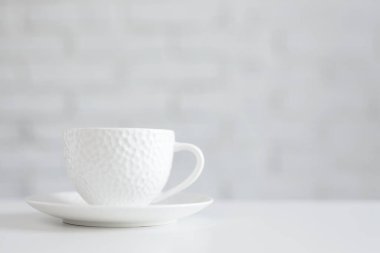 Beyaz masadaki beyaz fincanı kopyalama alanı olan beyaz arkaplanı kapat