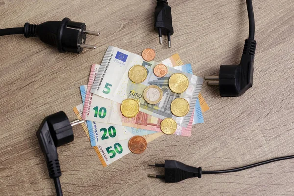 高価な電気の概念 テーブルの上の電気プラグとヨーロッパのお金の銀行券とコインの終わり — ストック写真