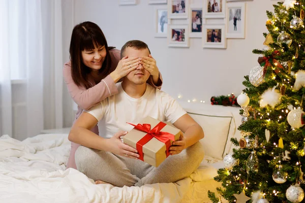 Weihnachtstradition Frau Schenkt Ihrem Mann Weihnachtsgeschenk Schlafzimmer Mit Geschmücktem Weihnachtsbaum — Stockfoto