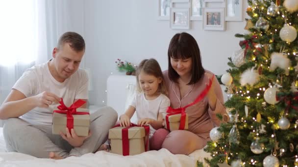在装饰过的圣诞树旁 快乐的家人打开圣诞礼物 — 图库视频影像