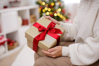 Noel arkaplanında kırmızı kurdeleyle el ele tutuşun.