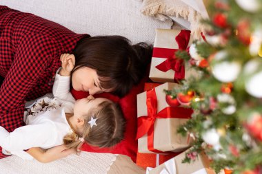 Anne ve kızı evde Noel ağacının altında yatıyor.