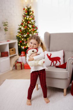 Mutlu küçük kız Noel süslemeli odada oyuncak tutuyor.