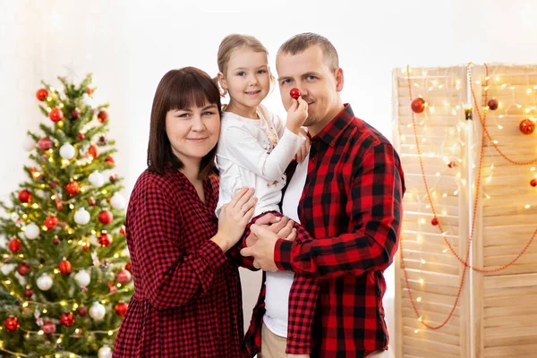 年轻的父母在家里的圣诞树旁牵着女孩的手 — 图库照片