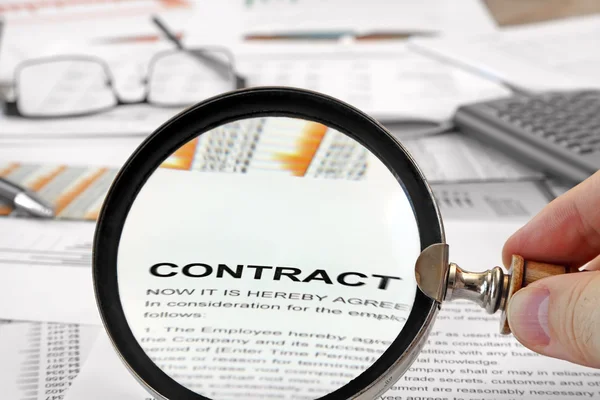 Vergrootglas over contract papers — Stockfoto