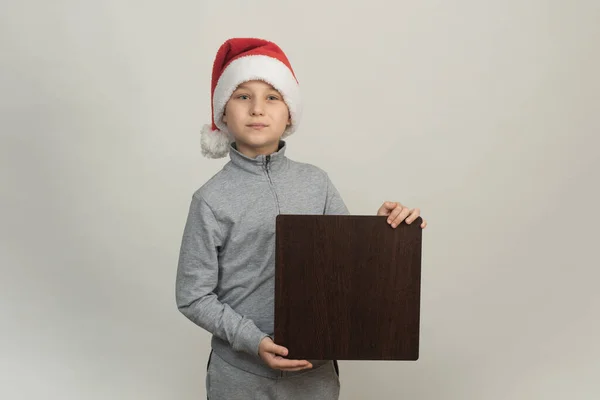 Santas boy helper holds a square board for advertising. mock up — Stock Photo, Image