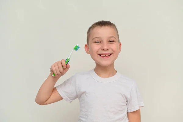 A smiling boy holds a toothbrush in his hand. mock up — Stock Photo, Image