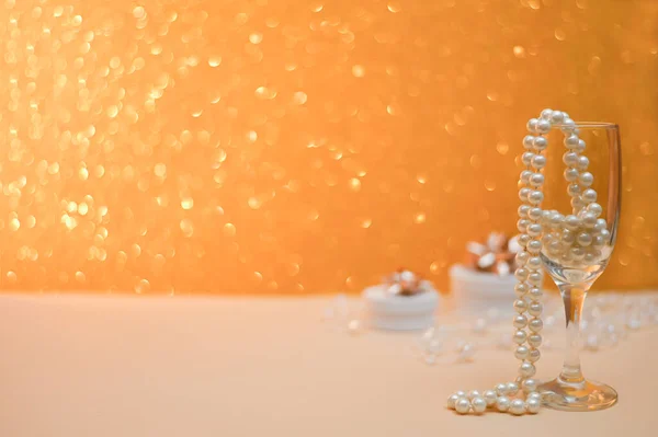 Cuentas de perlas en un vaso de vidrio. en un dorado. espacio de copia — Foto de Stock
