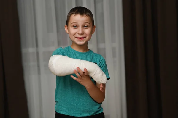 The boy has a cast on his arm and hes smiling. — Stock Photo, Image