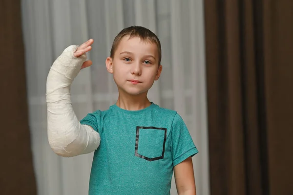 Menino mostra um braço quebrado em um elenco. — Fotografia de Stock