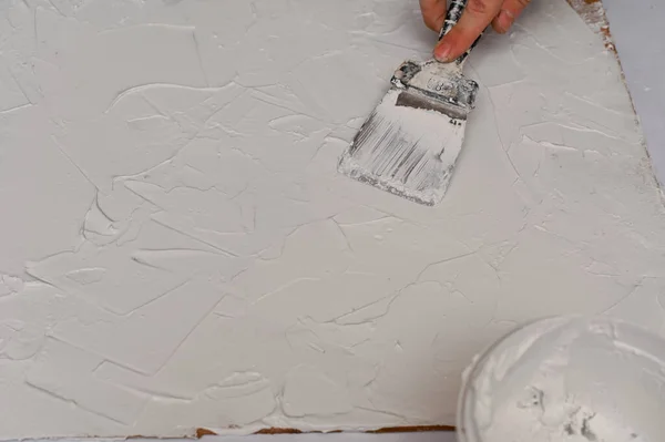Bir spatula ile fiberboard tabakasına macun katmanı uygulamak. konu çekimi için fotografik dokusal arkaplan oluşturma süreci.