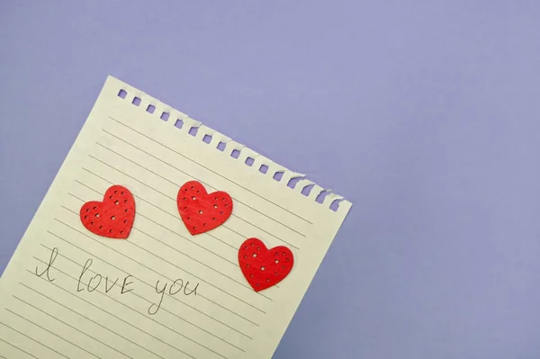 Te amo en un pedazo de papel con corazones. sobre un fondo púrpura. — Foto de Stock