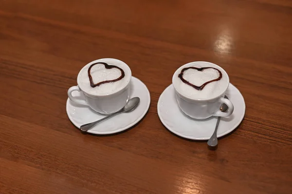 Duas xícaras de café em uma mesa de madeira, arte latte, com um coração — Fotografia de Stock