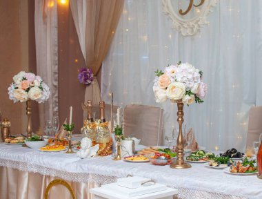 Kompozisyon, düğün masasının süslemesidir. Masada boş şarap kadehleri var. Çiçekler, abur cuburlar, şamdan..