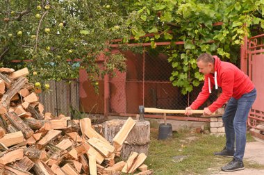 Bir adam odun keser ve onları yığının üzerine koyar. alternatif enerji kaynakları ve ekolojik doğal yakıtlar..