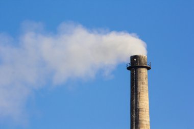 Mavi gökyüzü üzerinde endüstriyel duman baca