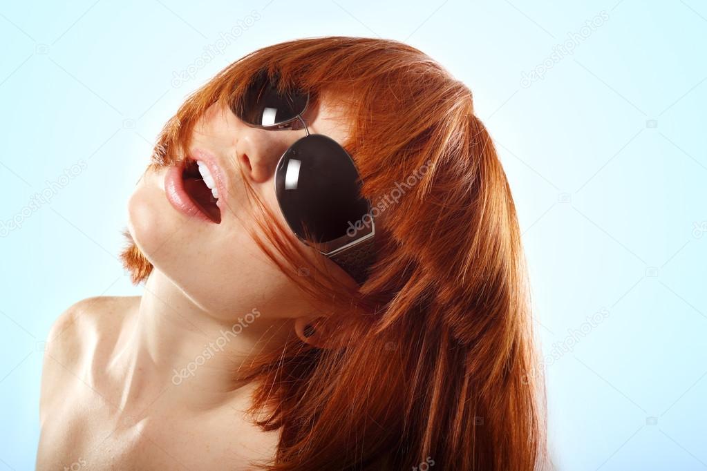 summer teen girl redheaded in sunglasses over blue