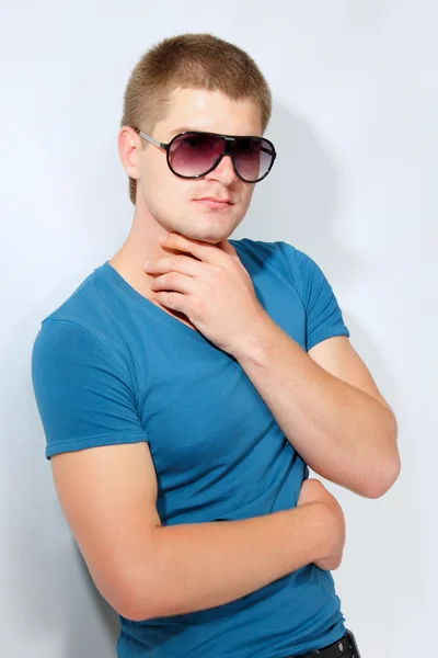 Mann junger schöner Athlet mit Sonnenbrille und blauem T-Shirt — Stockfoto