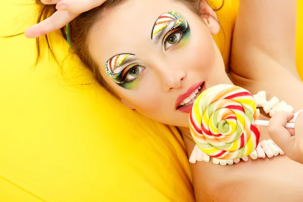 Žena olizuje candy s krásný make-up — Stock fotografie