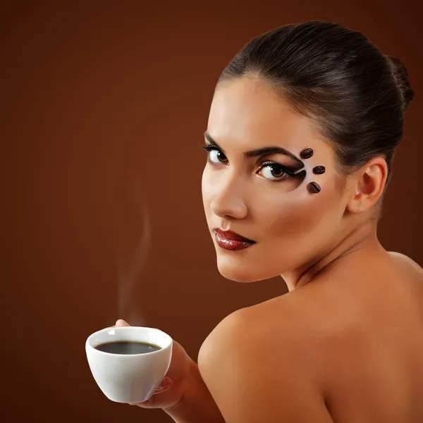 Жінка п'є каву з красивим макіяжем ізольовано на коричневому — стокове фото