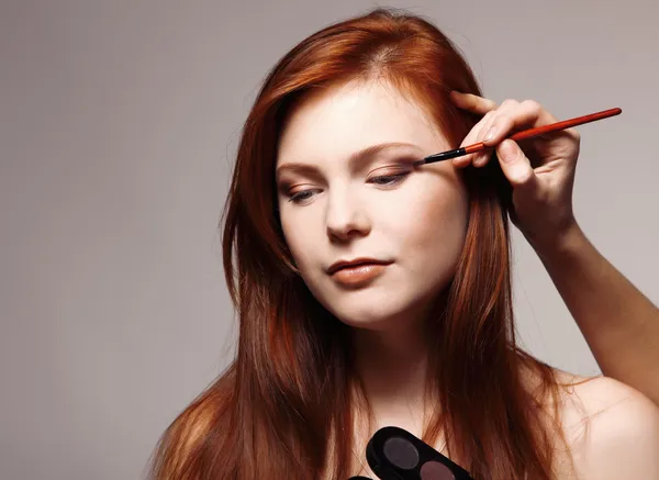 Portrait of beautiful young redheaded woman with esthetician making makeup — Stock Photo, Image