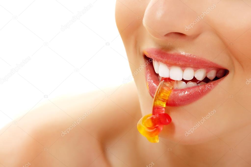 woman with cute sweet candy closeup in teeth