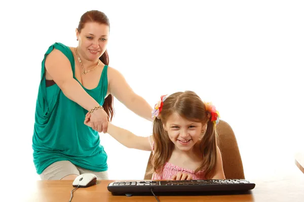 Girl with internet dependence playing with keyboard being dragged by mother from her computer — Stock Photo, Image