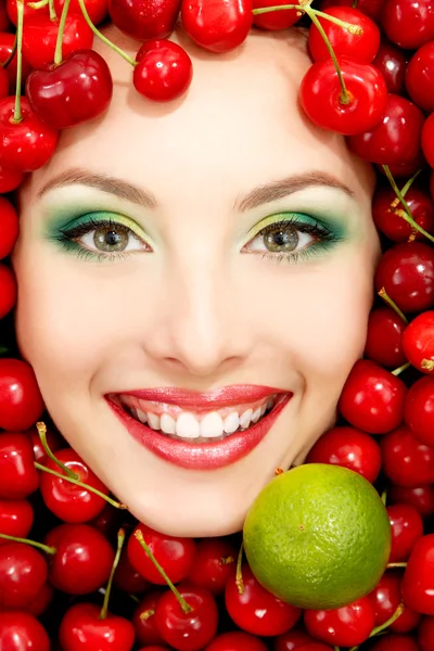 美丽的女人脸上用红色的成熟的大的新鲜的樱桃和石灰 — 图库照片
