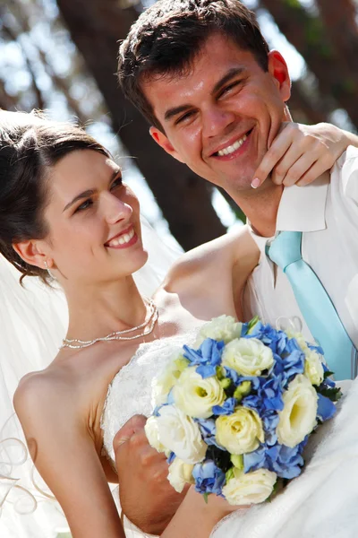 Schöne junge Braut umarmt Bräutigam in Liebe im Freien — Stockfoto