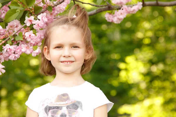 Портрет счастливой маленькой девочки возле японского вишневого дерева — стоковое фото