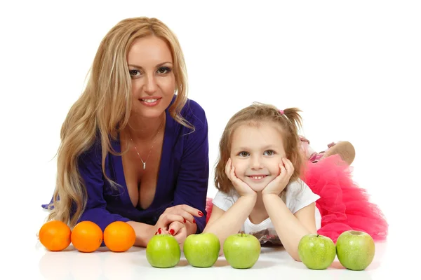 Madre con hija pequeña con manzanas y naranjas — Foto de Stock