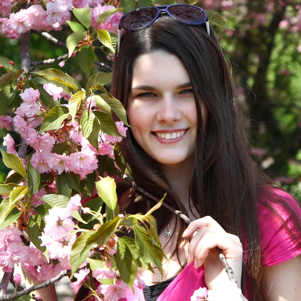 Красивая молодая женщина в весеннем саду рядом с цветущей вишней — стоковое фото