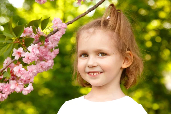 Japán cseresznyefa közelében boldog kislány portréja — Stock Fotó