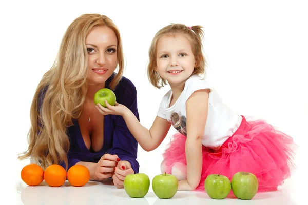 Мать с маленькой дочкой с яблоками и апельсинами — стоковое фото