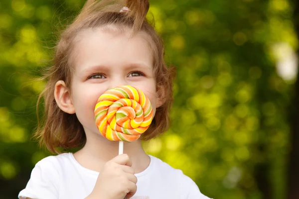 Happy little girl with sweet candy nature outdoor — Stock Photo, Image
