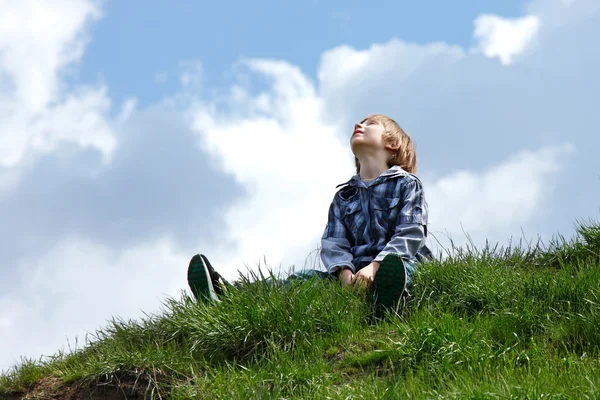 緑の芝生の上に座って幸せな少年 — ストック写真