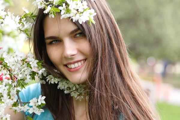 Bella giovane donna nel parco primaverile vicino al ciliegio in fiore — Foto Stock