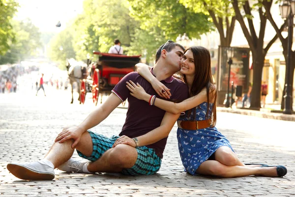 Amore storia di giovane coppia seduta su pietra pavimentazione abbraccio e bacio — Foto Stock